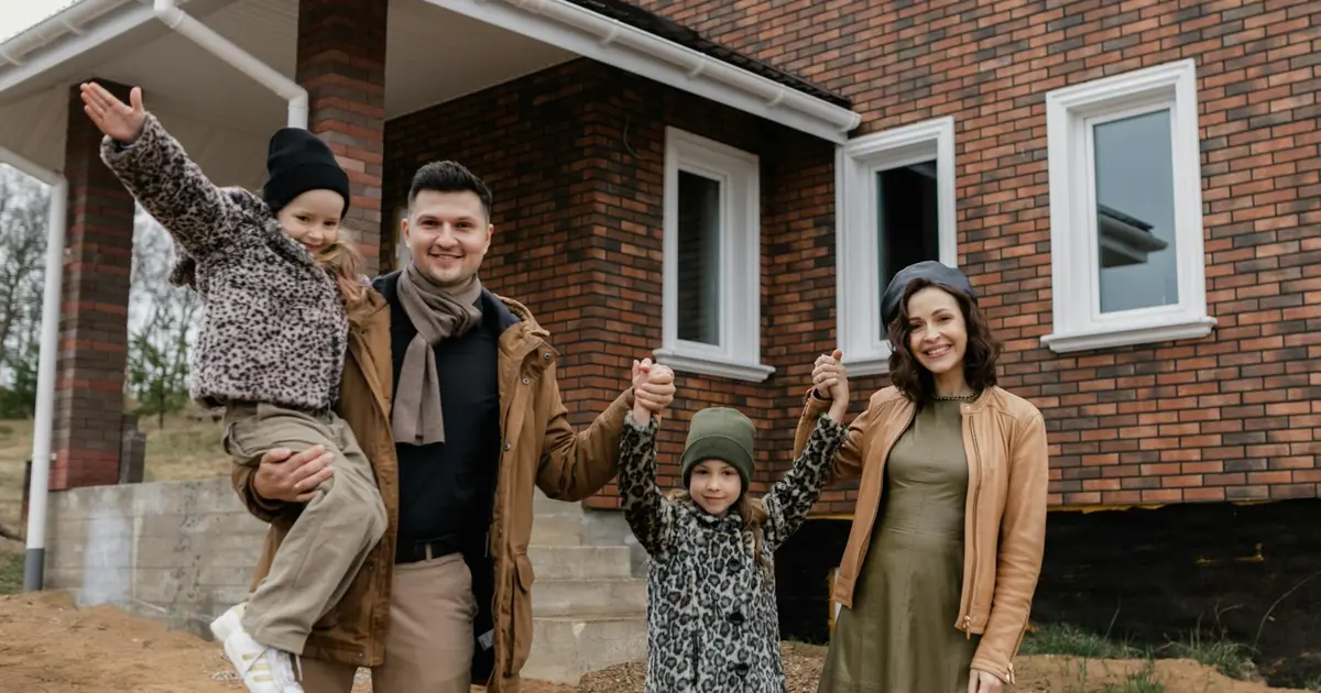 Famille devant une maison neuve qu'ils viennent d'acheter