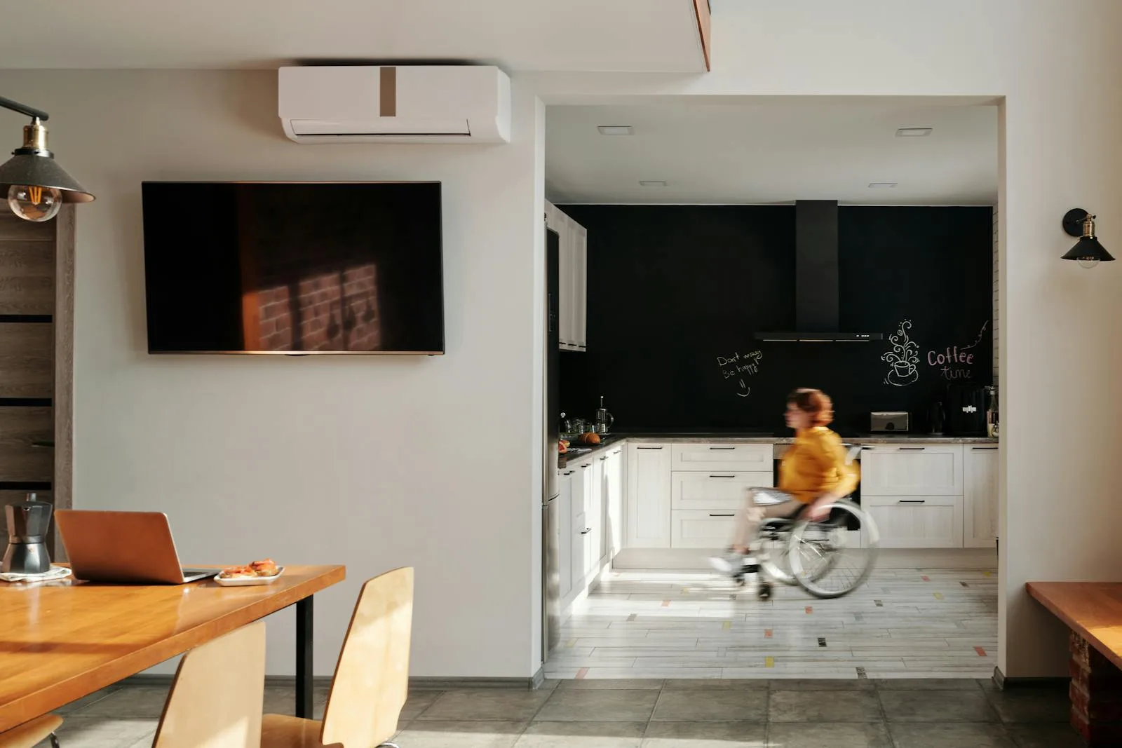 Personne en fauteuil roulant dans une cuisine adaptée d'un logement neuf accessible — PTZ handicap CMI AAH 2026